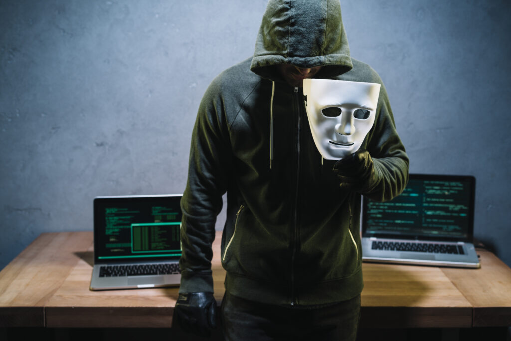 a man wearing a hoodie holding a mask showing how insider threats can be hidden in plain sight GRC, Insider Threats